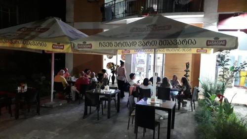 a restaurant with people sitting at tables under umbrellas at Apartment Zhemchuzhina Ureki in Ureki