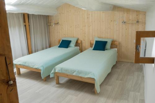 twee bedden in een kamer met houten wanden bij La Farigoule in Montbrun-les-Bains