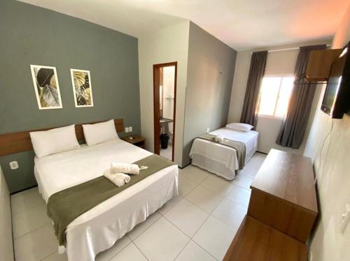 a hotel room with two beds and a television at Pousada Porto Rio in Parnaíba
