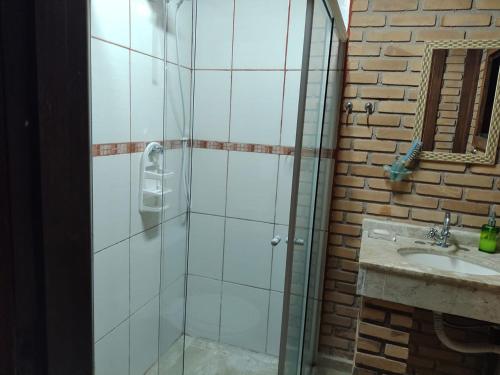 eine Dusche mit Glastür neben einem Waschbecken in der Unterkunft Charmosa casa com churrasq na praia de Camburi in São Sebastião