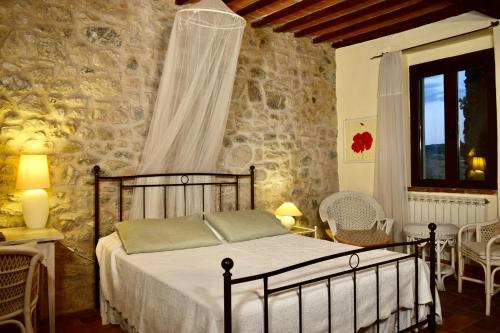 ein Schlafzimmer mit einem Bett und einer Steinmauer in der Unterkunft Villa San Sebastiano Montalcino in Montalcino
