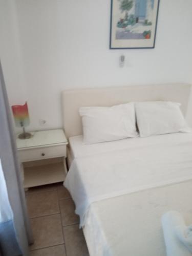 a white bedroom with a bed and a night stand at ERRIKA in Ermoupoli