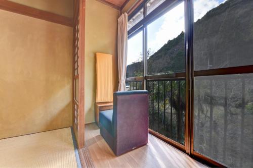 a room with a chair and a large window at 湯迫温泉旅館 in Ōda