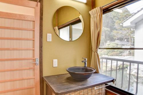 a bathroom with a bowl sink and a mirror at 湯迫温泉旅館 in Ōda