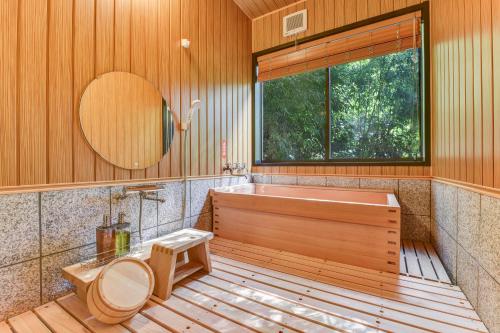 a bathroom with a tub and a toilet and a window at 湯迫温泉旅館 in Ōda