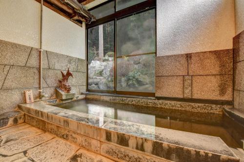 a large bath tub in a room with a window at 湯迫温泉旅館 in Ōda