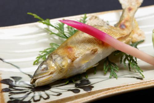 a piece of fish on a plate with a tooth pick at 湯迫温泉旅館 in Ōda