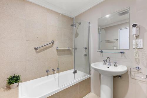 een badkamer met een douche, een wastafel en een bad bij Harbourside Studio Apartment in Kiama