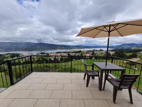 a table and chairs with an umbrella on a balcony at ReLuna Guatavita Glamping & Suites in Guatavita