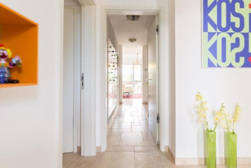 a hallway with white walls and tile floors and vases with flowers at Casa ECH in Gerbrunn