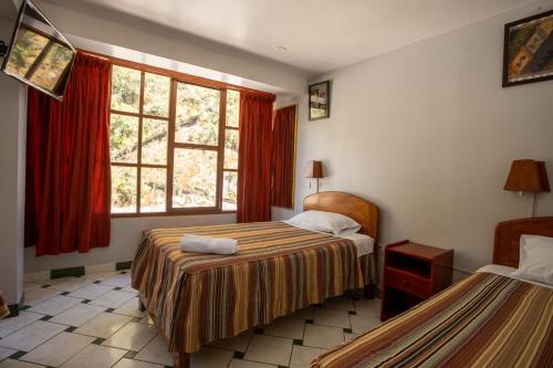 a hotel room with two beds and a window at Hostal La Payacha in Machu Picchu