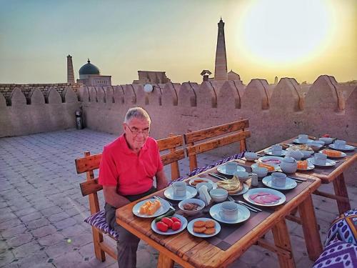een vrouw aan een tafel met borden eten bij HOTEL KALA KHIVA in Khiva