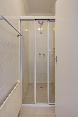 a shower with a glass door in a bathroom at Snow Ski Apartments 05 in Falls Creek