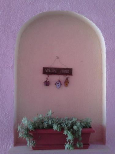 a sign on a wall with a plant in a planter at Smaragda Hotel in Marathokampos