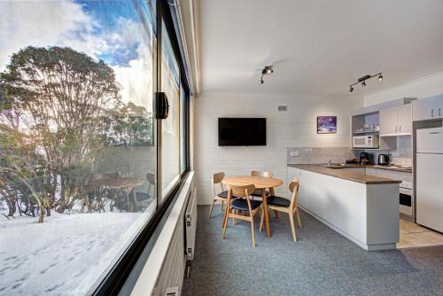 a kitchen with a table and a large window at Snow Ski Apartments 06 in Falls Creek