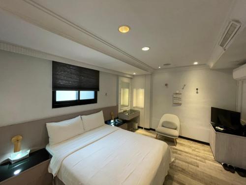 una camera con un grande letto bianco e una sedia di Sunrise Hotel a Taipei