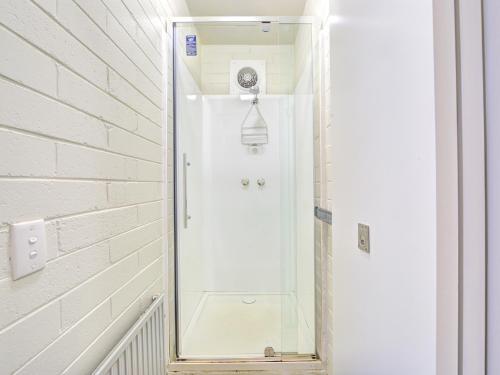 a shower with a glass door in a bathroom at Snow Ski Apartments 27 in Falls Creek