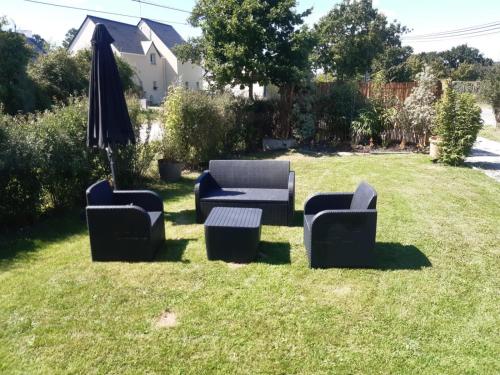 a group of chairs and an umbrella in the grass at Maison entre Mer et Brière. Proche de La Baule et de Guérande. in Saint-André-des-Eaux