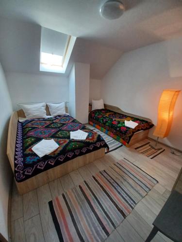 2 Betten in einem kleinen Zimmer mit Fenster in der Unterkunft Casa Pandrea in Cîrţişoara