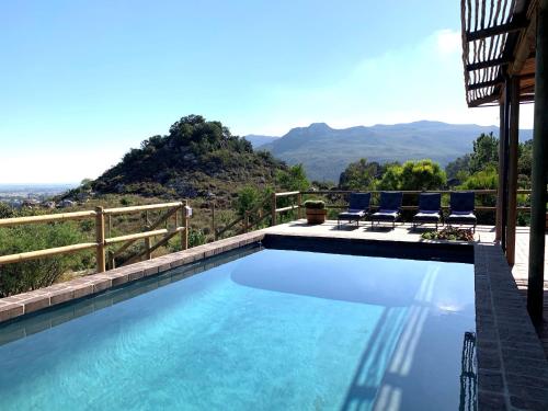 a swimming pool with chairs and mountains in the background at 7 Koppies in Franschhoek