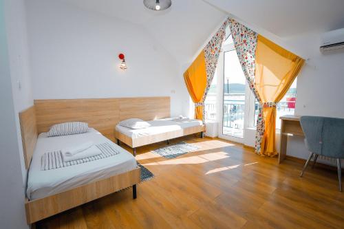 a bedroom with two beds and a desk and a window at Laguna Beach Club Bazaleti Lake in Dushetʼi
