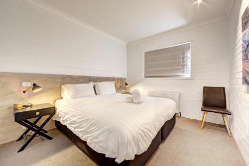 a bedroom with a large bed and a chair at Snow Ski Apartments 39 in Falls Creek