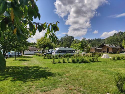 a field with trees and a camper in the background at Camping Prima in Týn nad Vltavou