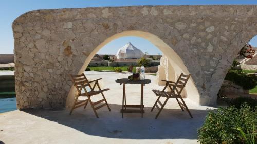 une arche avec une table et deux chaises et une mosquée dans l'établissement Al Nyhaya, à Siwa