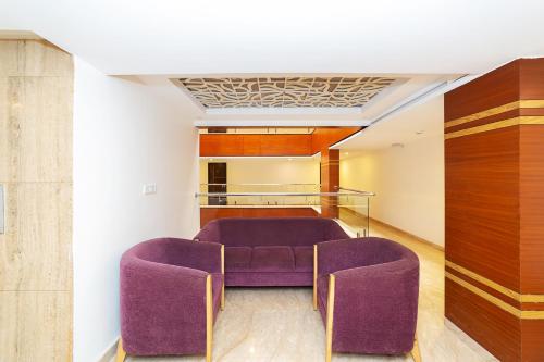 a room with purple chairs and a glass table at Icon Regency by Bhagini in Bengaluru