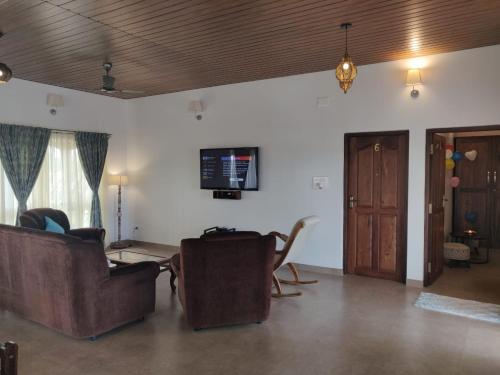 a living room with chairs and a tv on the wall at Elegant holiday homes Coorg in Madikeri