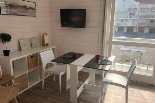 une salle à manger avec une table et des chaises et une télévision dans l'établissement Studio, proche du Touquet, tout équipé à 100m de la plage, à Stella-Plage