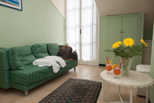 Hotel Splendid Mare في لايقويليا: غرفة معيشة مع أريكة خضراء وطاولة