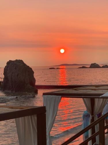 a sunset on the beach with a curtain and the ocean at Stefania lovely studio in Aghia Marina