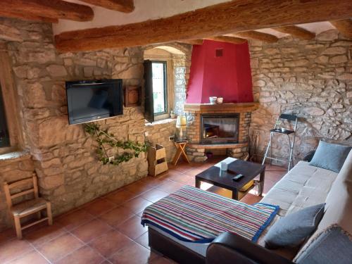 sala de estar con pared de piedra, sofá y TV en Cal Calçó en Pinós