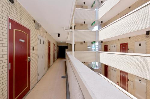 a hallway of a school with red doors and white walls at Sky Heart Hotel Kawasaki in Kawasaki