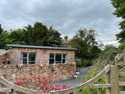 a brick house with a stone wall and a fence at Pine Tree Lodge, Bridgnorth in Bridgnorth