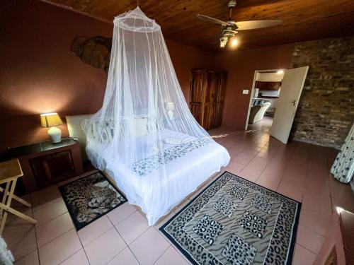 a bedroom with a bed with a mosquito net at Masasana’s Rest in Hazyview