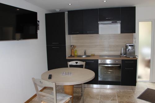 a kitchen with black cabinets and a table with chairs at Appartement PERIGUEUX Garage Fibre Climatisation in Périgueux