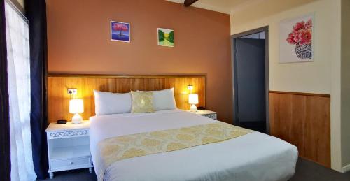 a bedroom with a bed and two night stands with lamps at Highway Motor Inn Taree in Taree