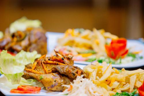 two plates of food with meat and vegetables on a table at LEYSHOF HOTEL in Mwanza