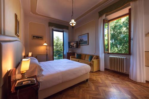 a bedroom with a bed and a couch and a window at Villa Scacciapensieri Boutique Hotel in Siena
