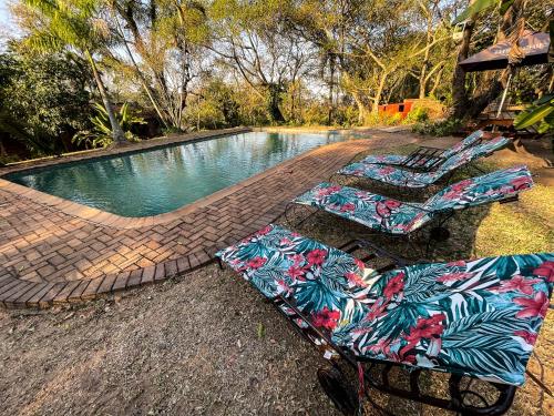 two chairs and a swimming pool with a table at Masasana’s Rest in Hazyview