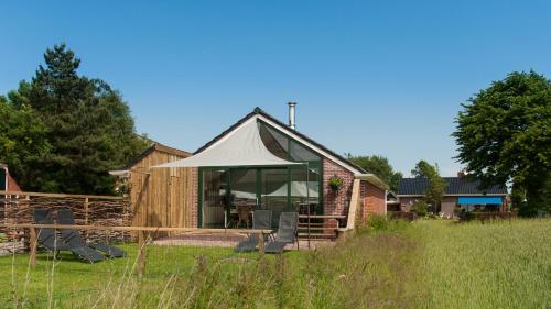 una casa con una tienda y sillas en un campo en Beleef het Noorden, en Groninga