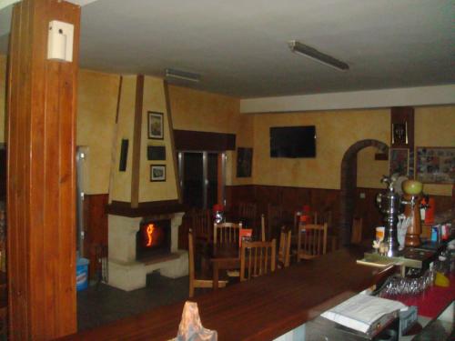 a living room with a fireplace and a table and chairs at Hostal Poncebos in Poncebos