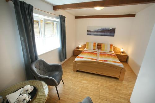 1 dormitorio con 2 camas, silla y ventana en Winzerzimmer - Weingut Tinhof, en Eisenstadt