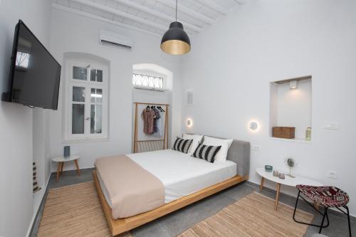 a white bedroom with a bed and a tv at Avli Suites in Mikonos