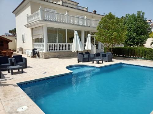 a swimming pool with chairs and umbrellas in front of a house at Villa de lujo en Torremolinos in Torremolinos