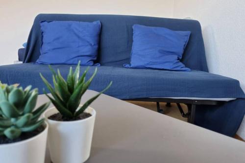 ein blaues Bett mit blauen Kissen und einen Tisch mit Pflanzen in der Unterkunft Neu Whng. Zentrum ruhig best place Netflix Garage in Gießen