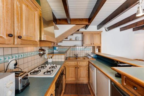 une cuisine avec des armoires en bois et un four à plaques de cuisson dans l'établissement Le Triplex Carnot - Apartment with air conditioning for 5 people, à Annecy