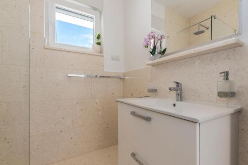 a white bathroom with a sink and a shower at Villa Buzuk in Vodice